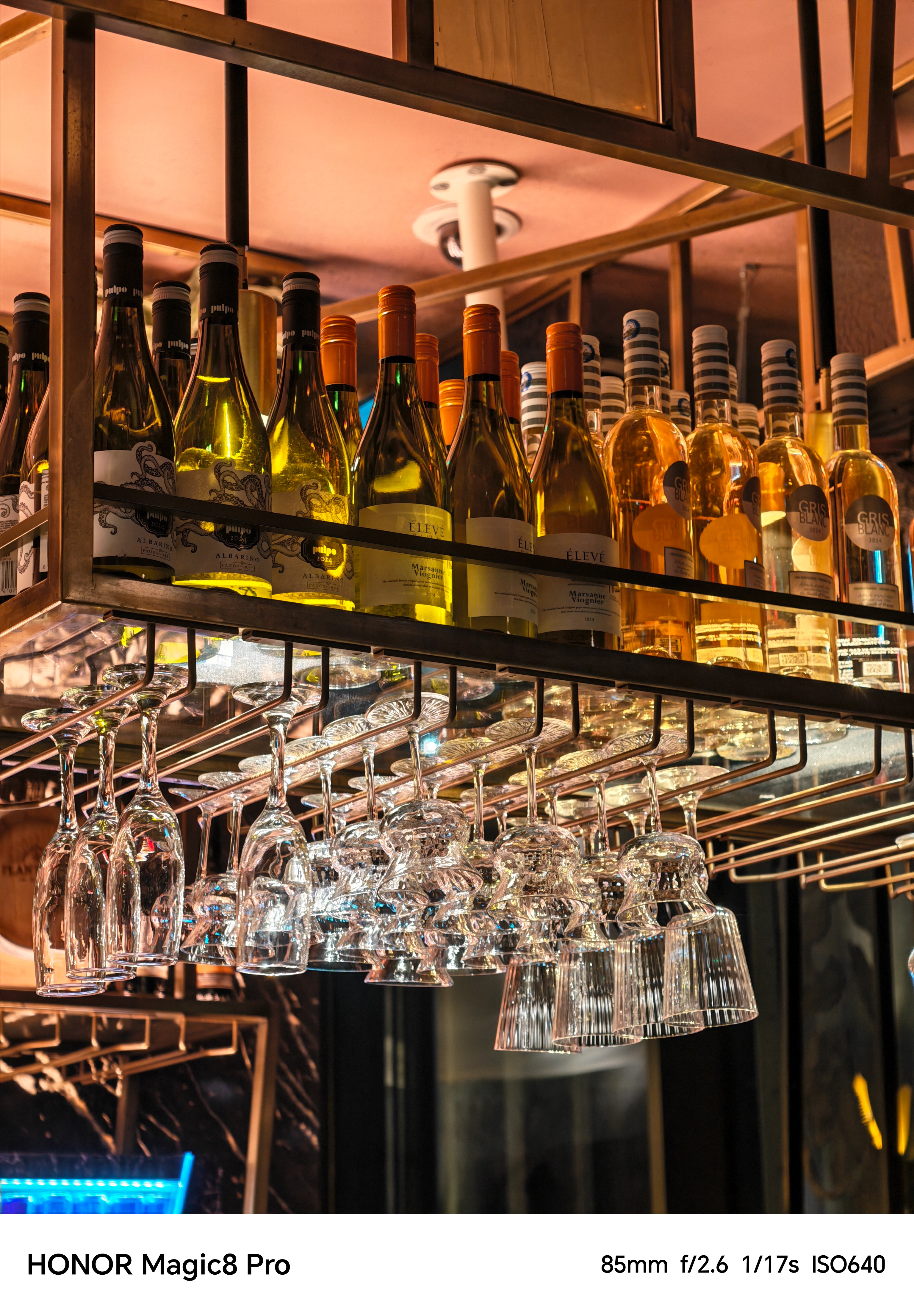Bottles and glasses lined up on a bar at night shot on an Honor Magic 8 Pro