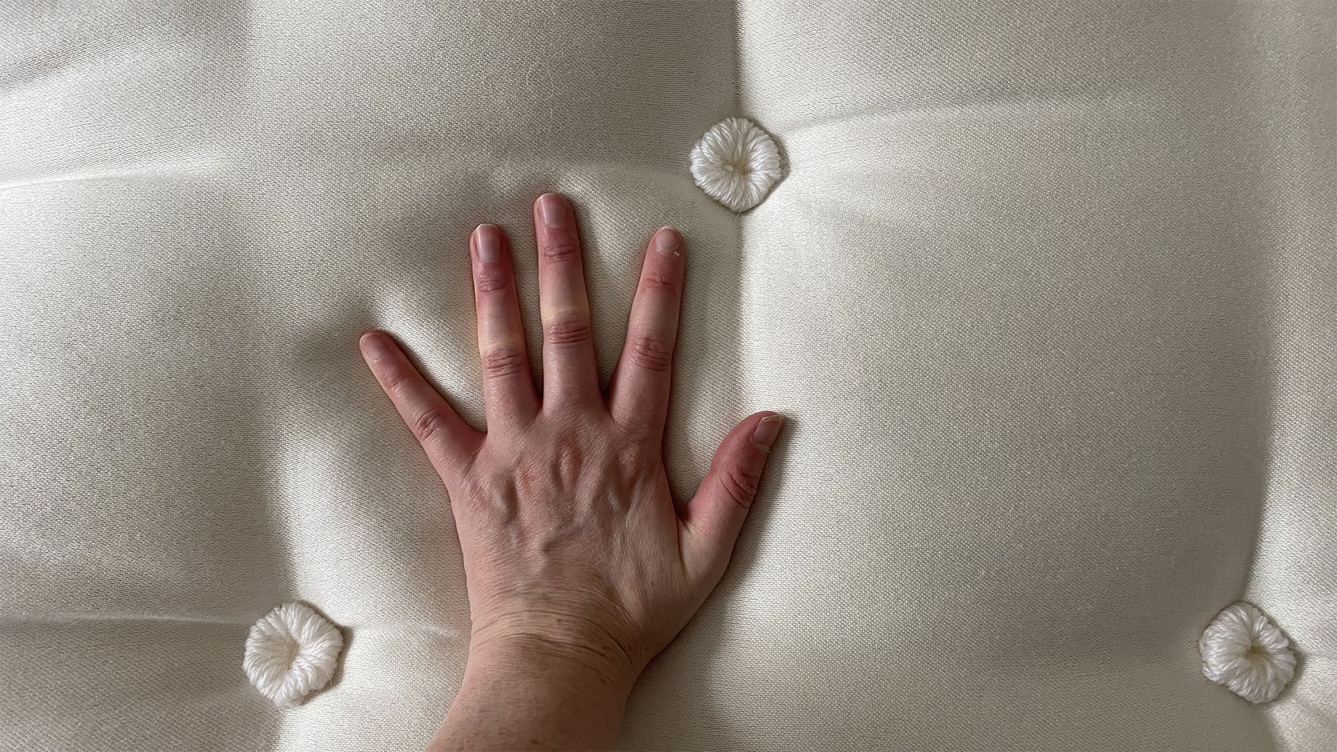 A hand touches the surface of the Simba Earth Escape Mattress to check the temperature regulation