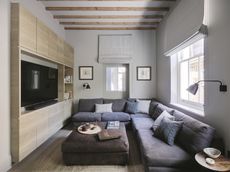 a living room with a grey sofa and a media wall with a tv and soundbar