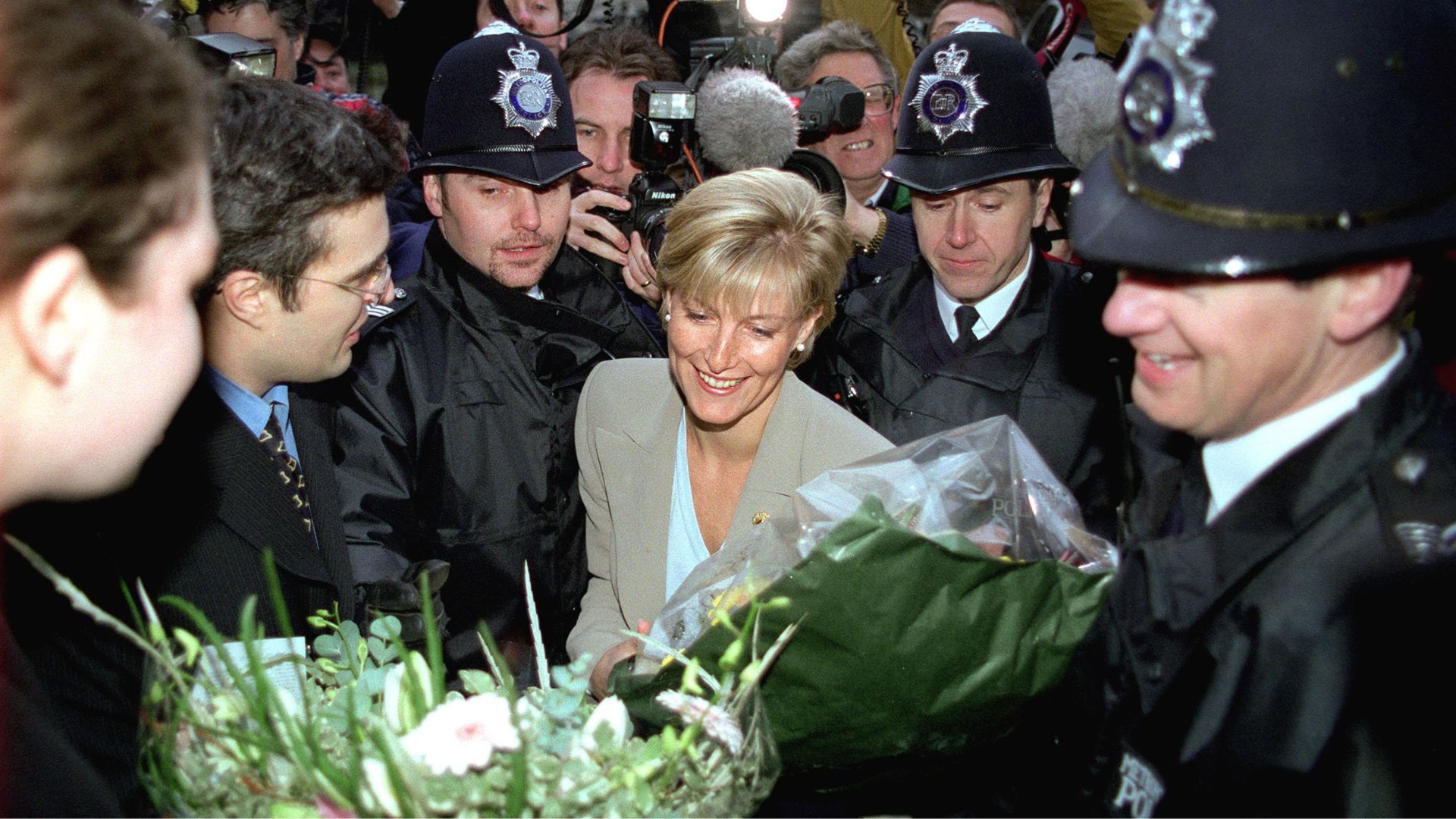 Duchess Sophie arrives at her PR firm in London surrounded by police and receiving flowers after announcing her engagement to Prince Edward