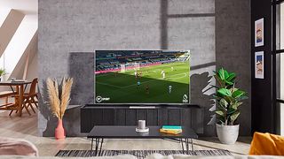 The Samsung QN85A Neo QLED 4K TV in a grey room showing a football match