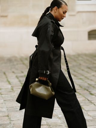 woman in a black coat and olive green bag