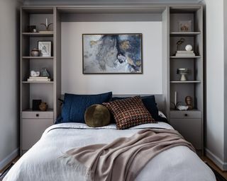 guest bedroom with grey walls and murphy bed with shelving on either side