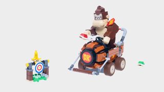 Lego Donkey Kong and kart along with a target bearing a banana skin on top, all against a plain background