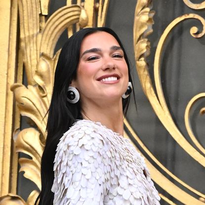 a woman with long black hair in a textured jacket