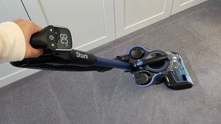 The Shark Anti Hair Wrap Cordless Upright Vacuum Cleaner with PowerFins, Powered Lift-Away & TruePet ICZ300UKT being used to clean carpet with a focus on the LCD screen