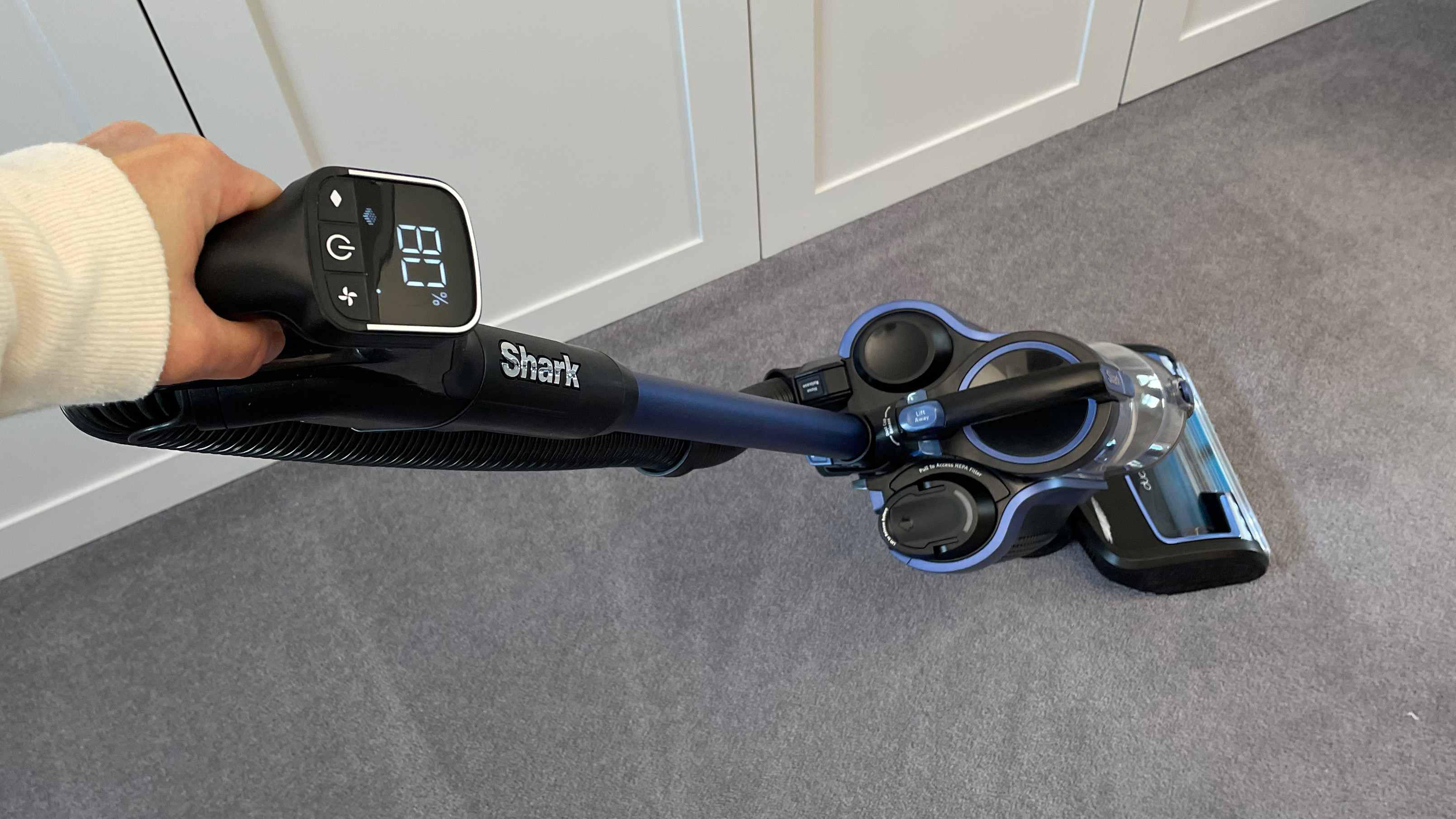 The Shark Anti Hair Wrap Cordless Upright Vacuum Cleaner with PowerFins, Powered Lift-Away & TruePet ICZ300UKT being used to clean carpet with a focus on the LCD screen