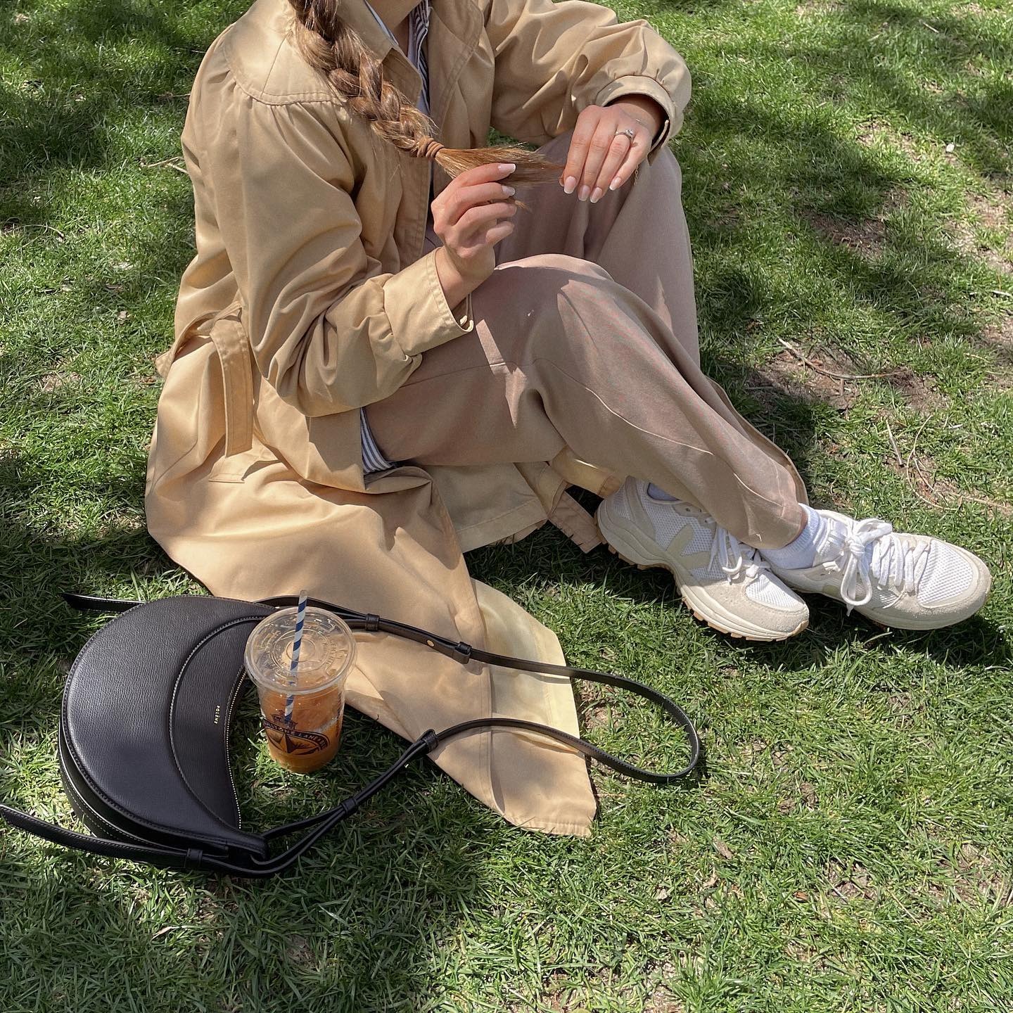 Influencer wears trench coat and khaki trousers and mesh sneakers.