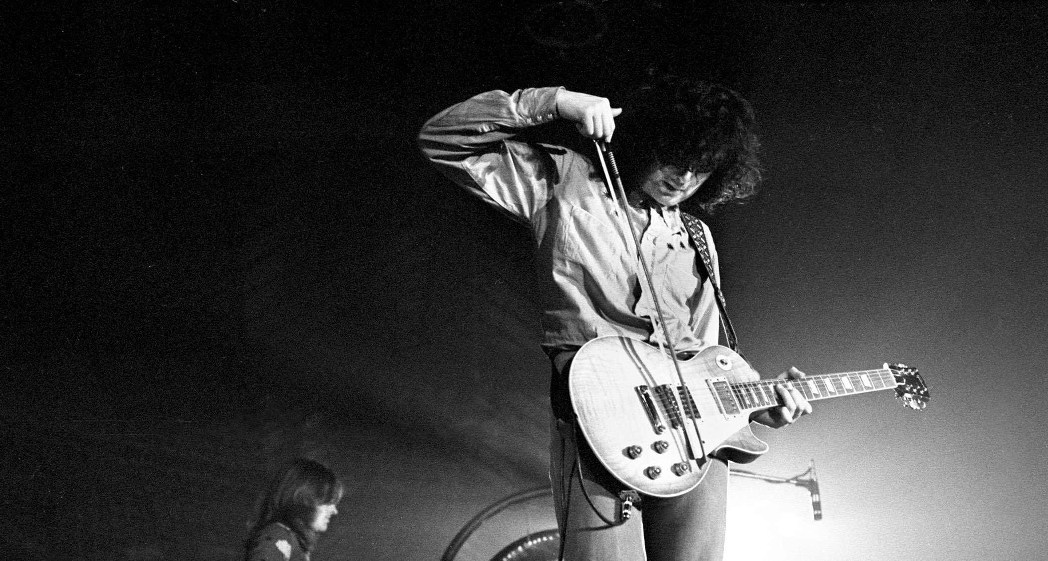 A black-and-white image of Jimmy Page using a violin bow on his 1959 Gibson Les Paul Standard.