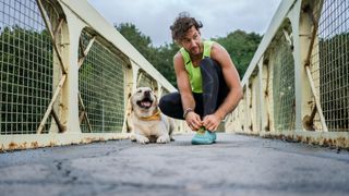 Man kneeling on bridge with dog