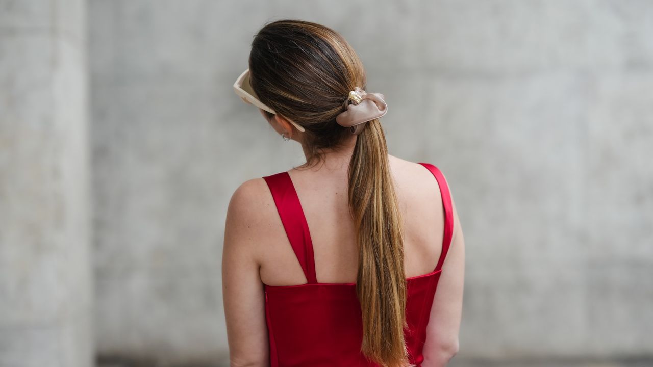 Maria Rosaria Rizzo wears a red silk lustrous top, a hair scrunchie, earrings, sunglasses, during a street style fashion photo session, on May 08, 2024 in Paris, France.