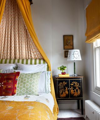 Yellow canopy bed with green, red and yellow bedding, chinese bedside cabinet, side lamp and yellow blinds