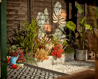 A decked area in backyard with feature fence decor created with colorful exterior paint and stencils