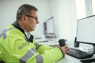 A policeman using a computer in an office