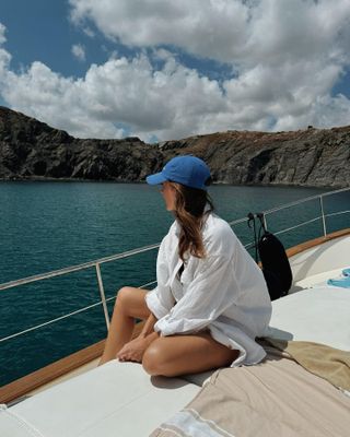 Woman on boat wearing white shirt and blue cap