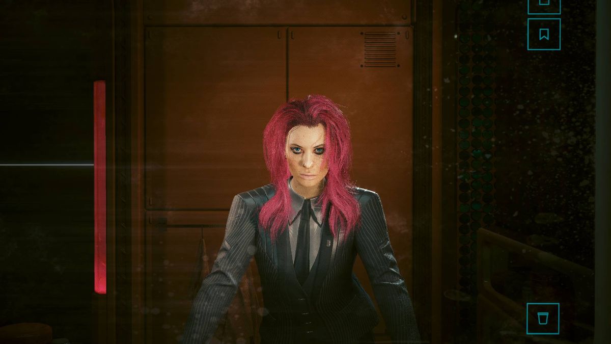 Female V with pink hair wearing a suit standing in front of the mirror in Cyberpunk 2077.