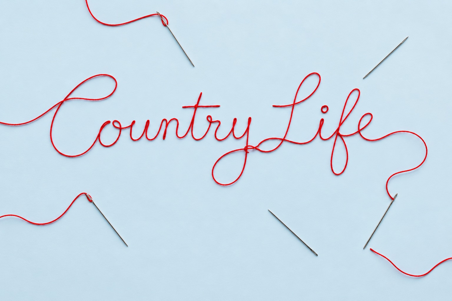 The words 'Country Life' written out in red looping thread on a pale blue background
