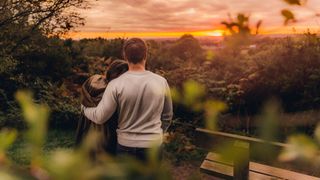 Back view of couple in love in fall nature watching sunset