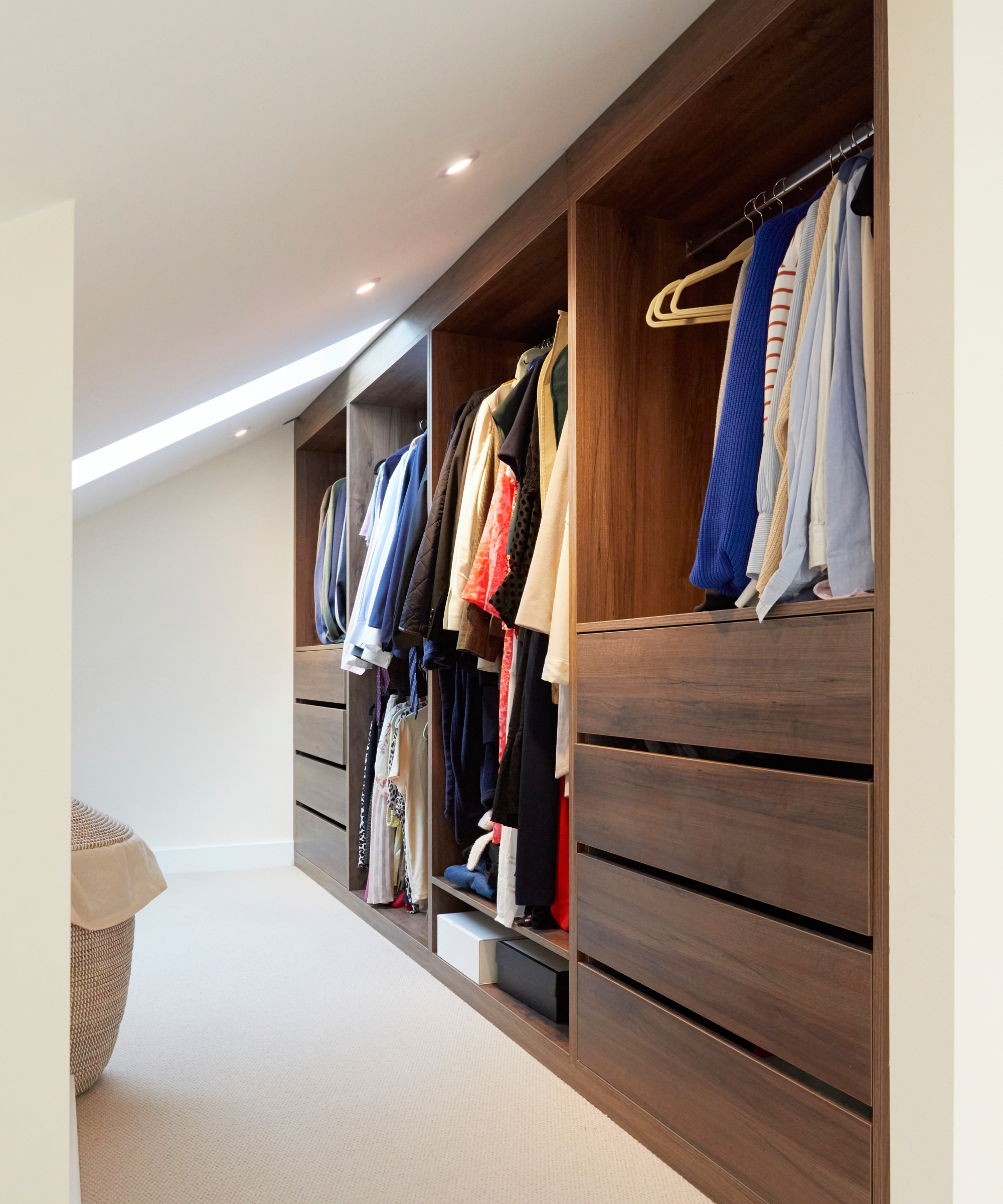 dressing room area with fitted dark wood wardrobes built into sloping roof section of a dormer loft extension