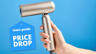 A woman's hand holding the Dreame Pocket Neo air styler in gold with a price drop tag.