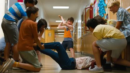 A gang of kids holds a woman down while another kid raises an ax to strike her