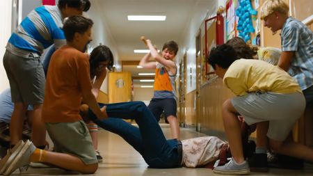 A gang of kids holds a woman down while another kid raises an ax to strike her