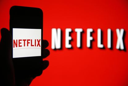 The Netflix logo is shown on a phone screen 