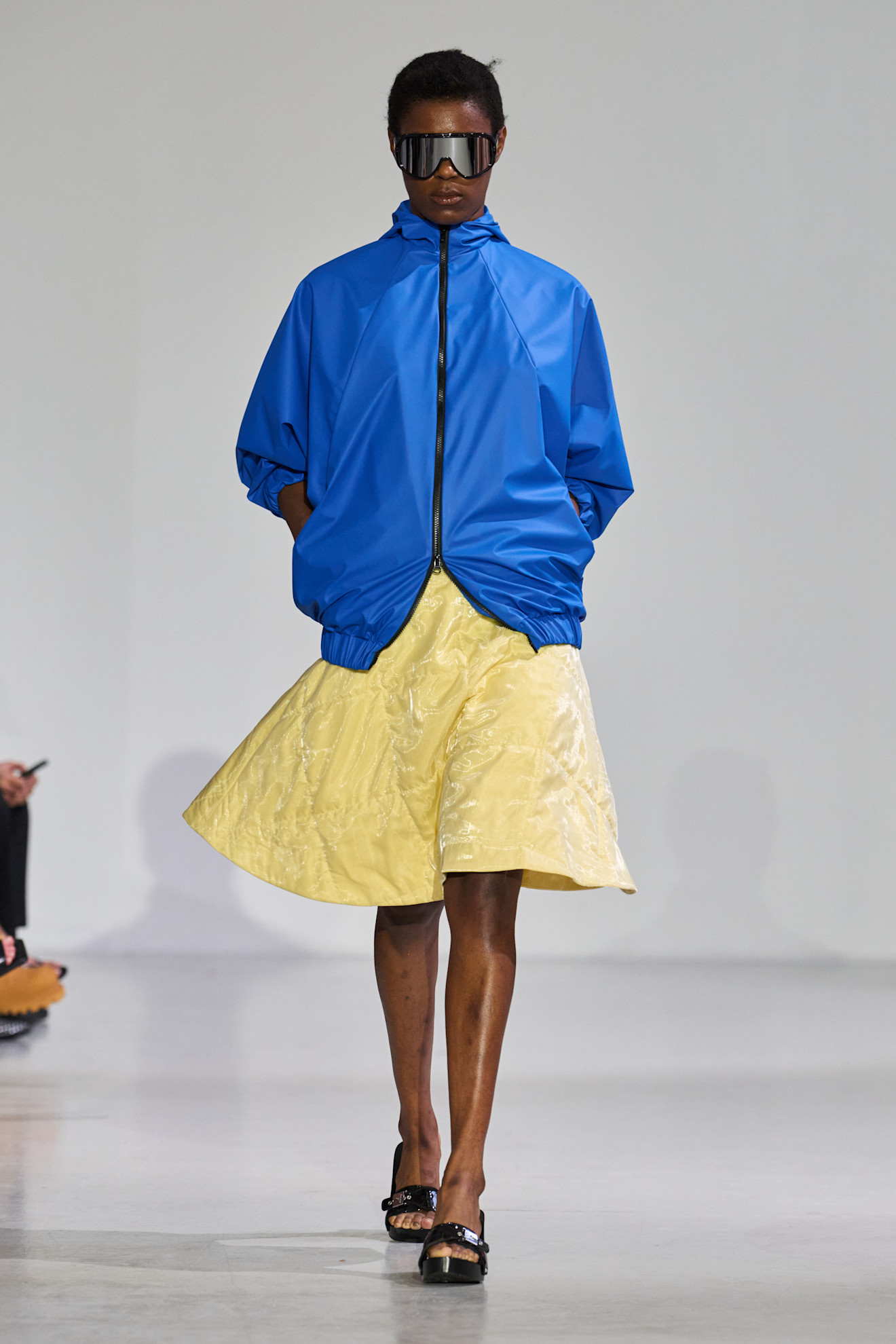 Woman in blue sporty jacket and a yellow skirt