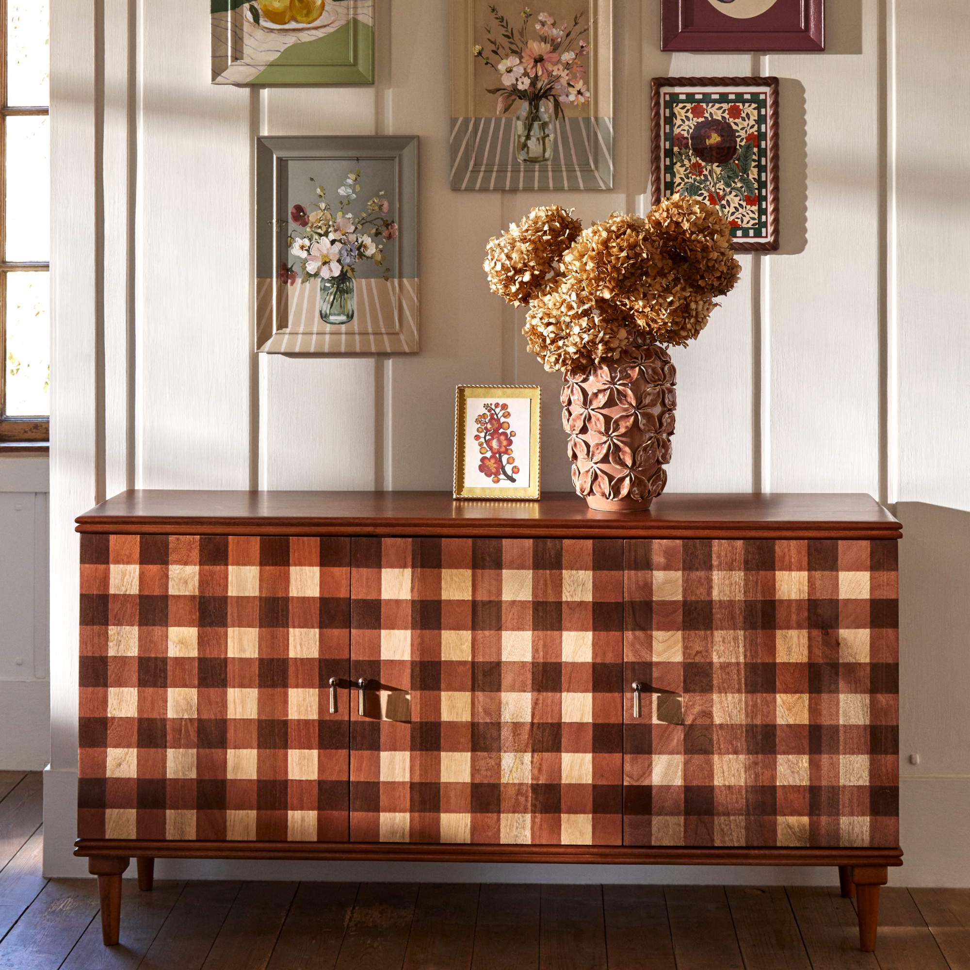 Dunelm Posie gingham sideboard against a panelled wall with a vase of dried hydrangeas on top and framed wall art above it