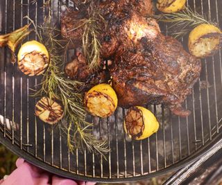 A cut of lamb barbequing on the grill with sprigs of rosemary.