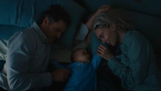 a father and mother with a baby boy in a blue jumper