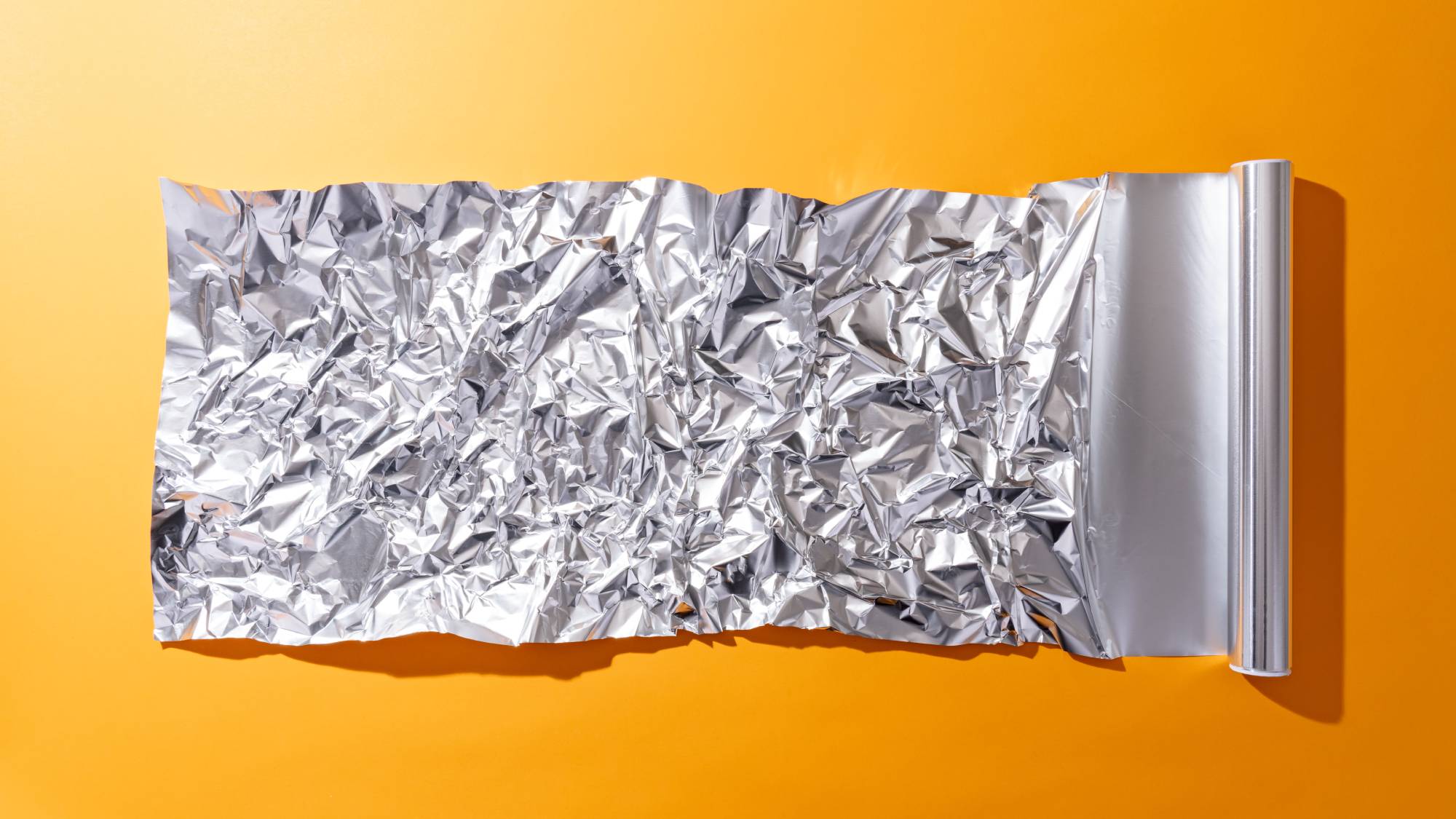 Roll of tin foil on orange background