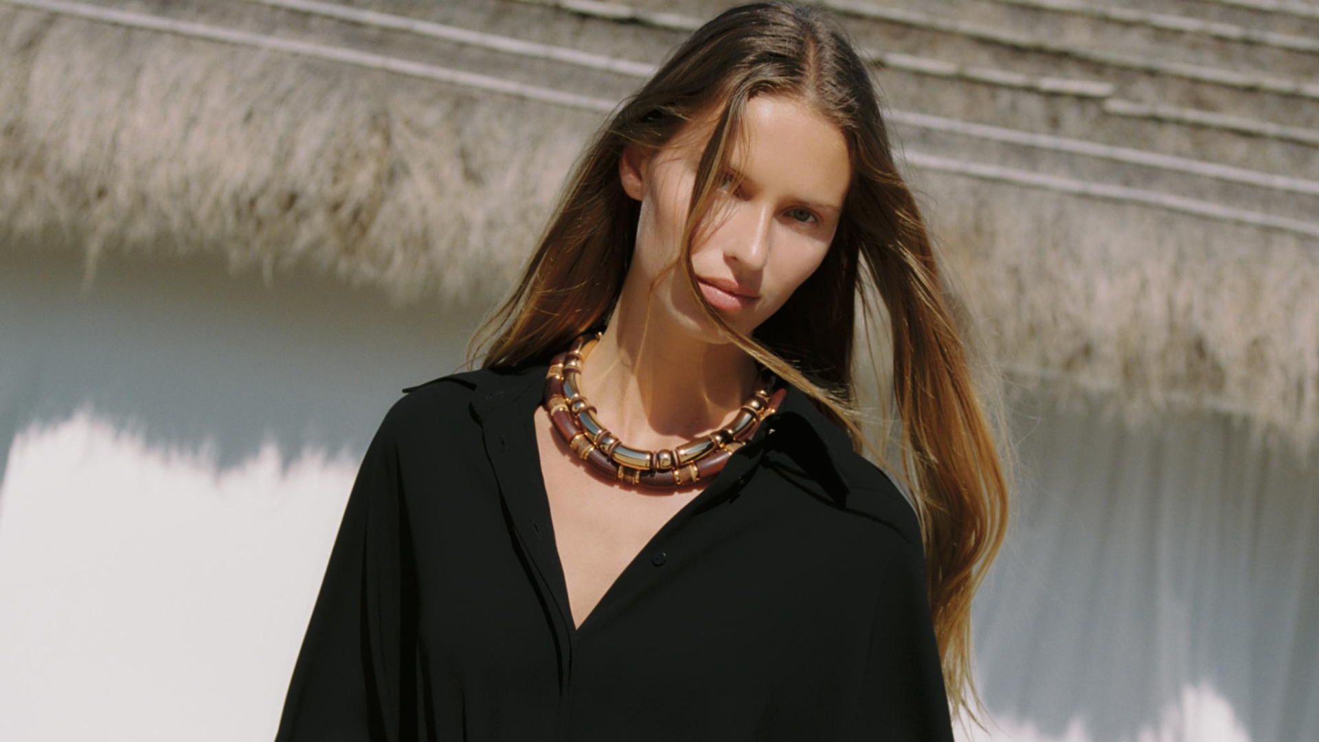 zara model wearing gathered kimino skirt in front of straw roof house
