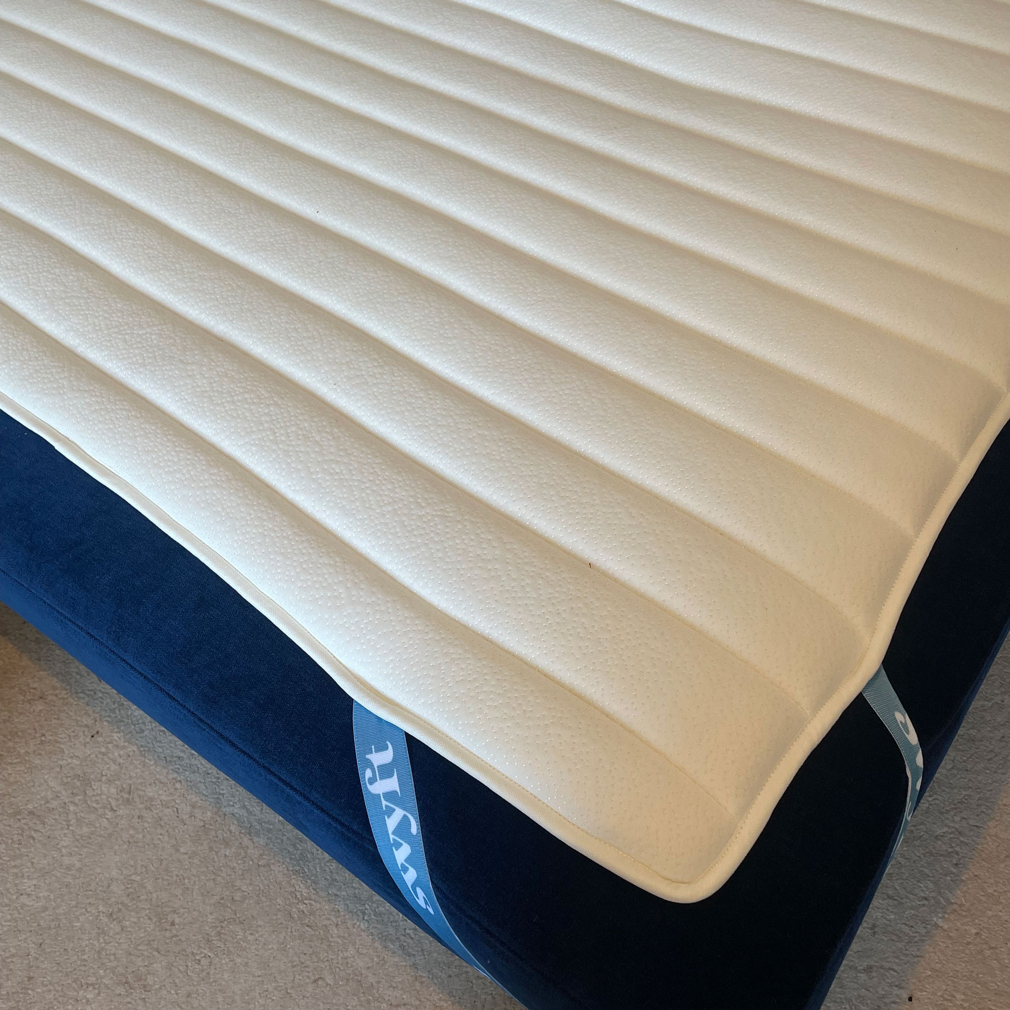 Bottom corner Swyft model 08 two seater sofa bed in Indigo velvet showing Swyft mattress topper