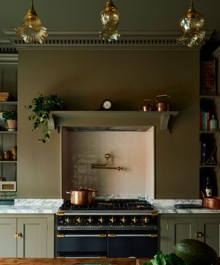 dark green kitchen with brass fixtures and black oven