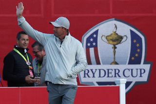 Padraig Harrington waves in front of the Ryder Cup logo