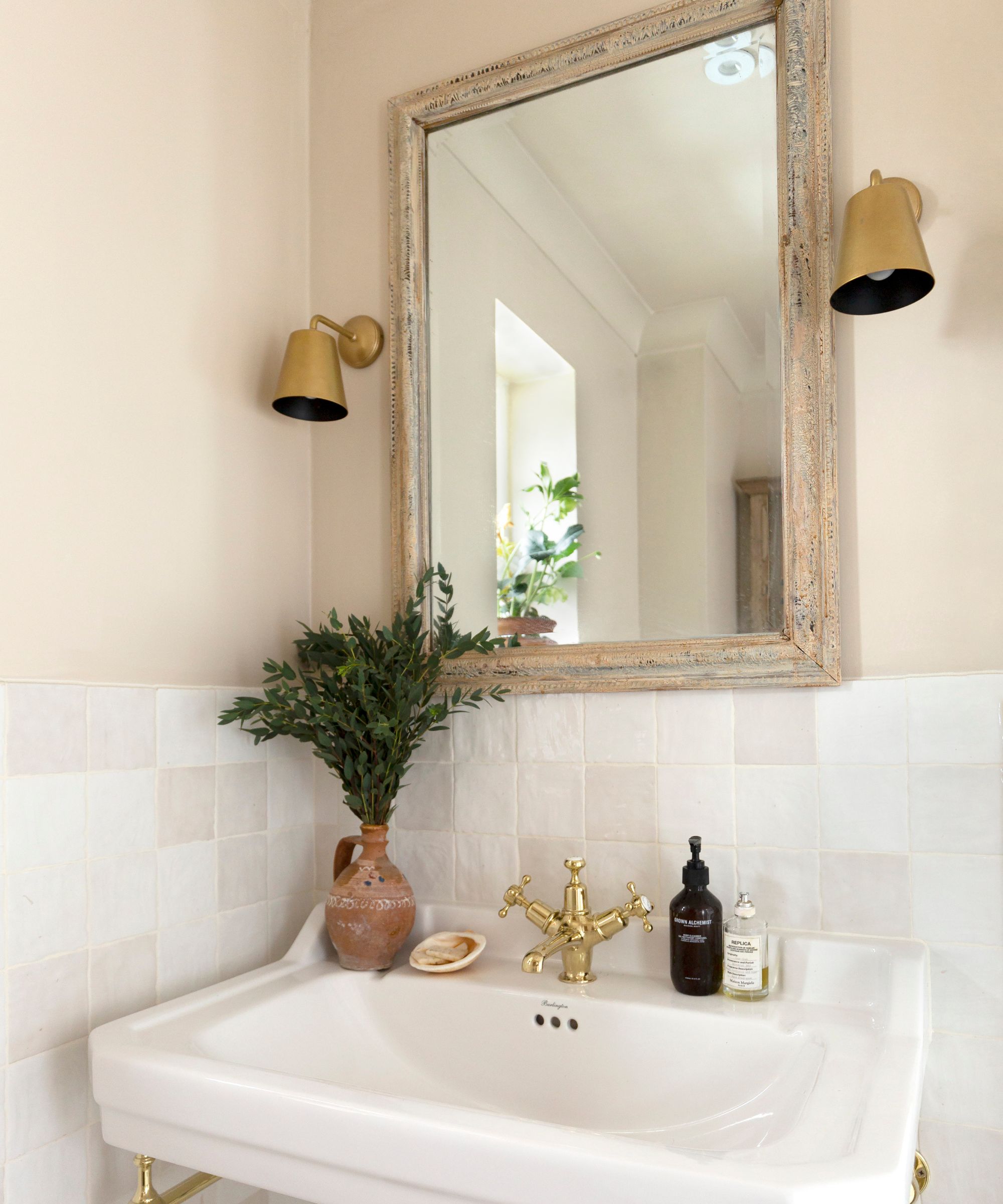 A bathroom vanity area with pale pink walls and white square tiles