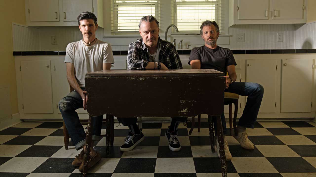 Mike Patton and the Avett Brothers seated at a kitchen table