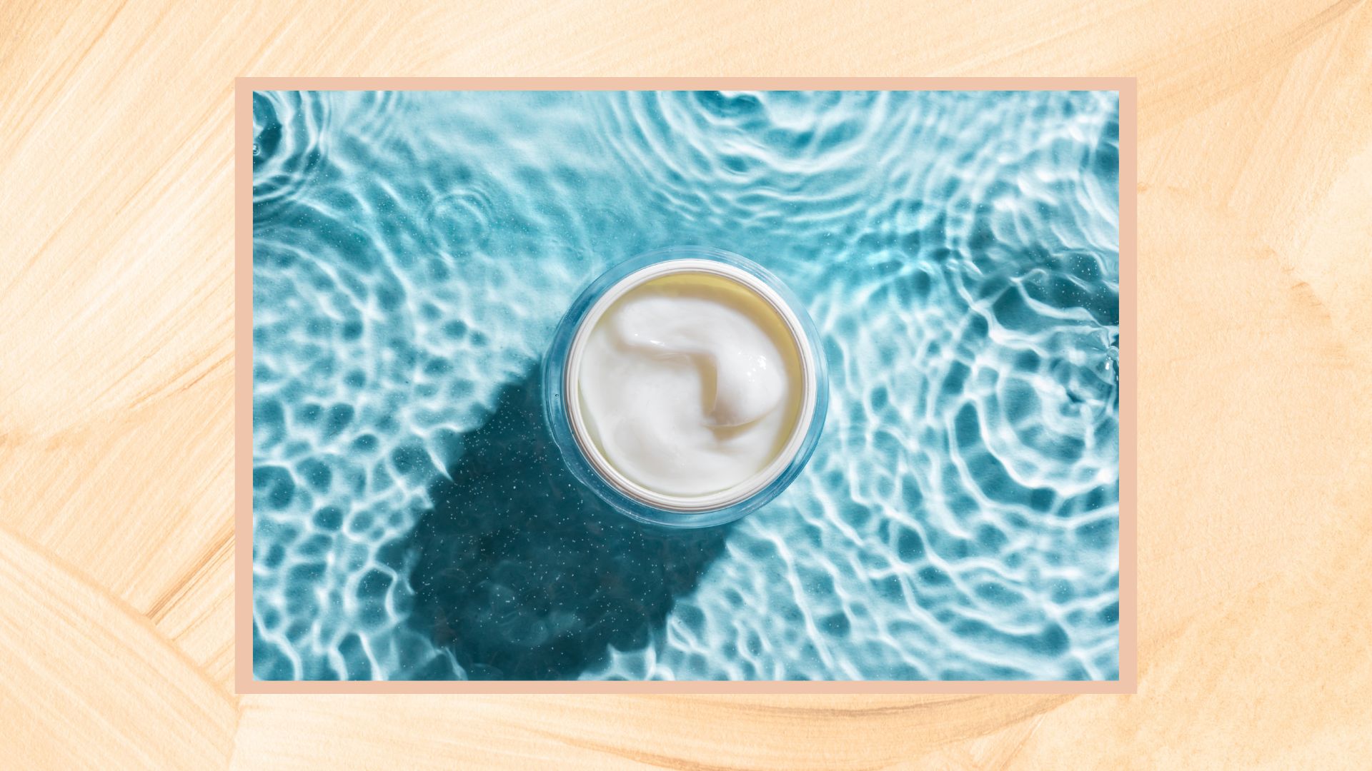 a yellow frame containing an image of a blue watery pool and a pot of moisturiser, seen from above with the lid off