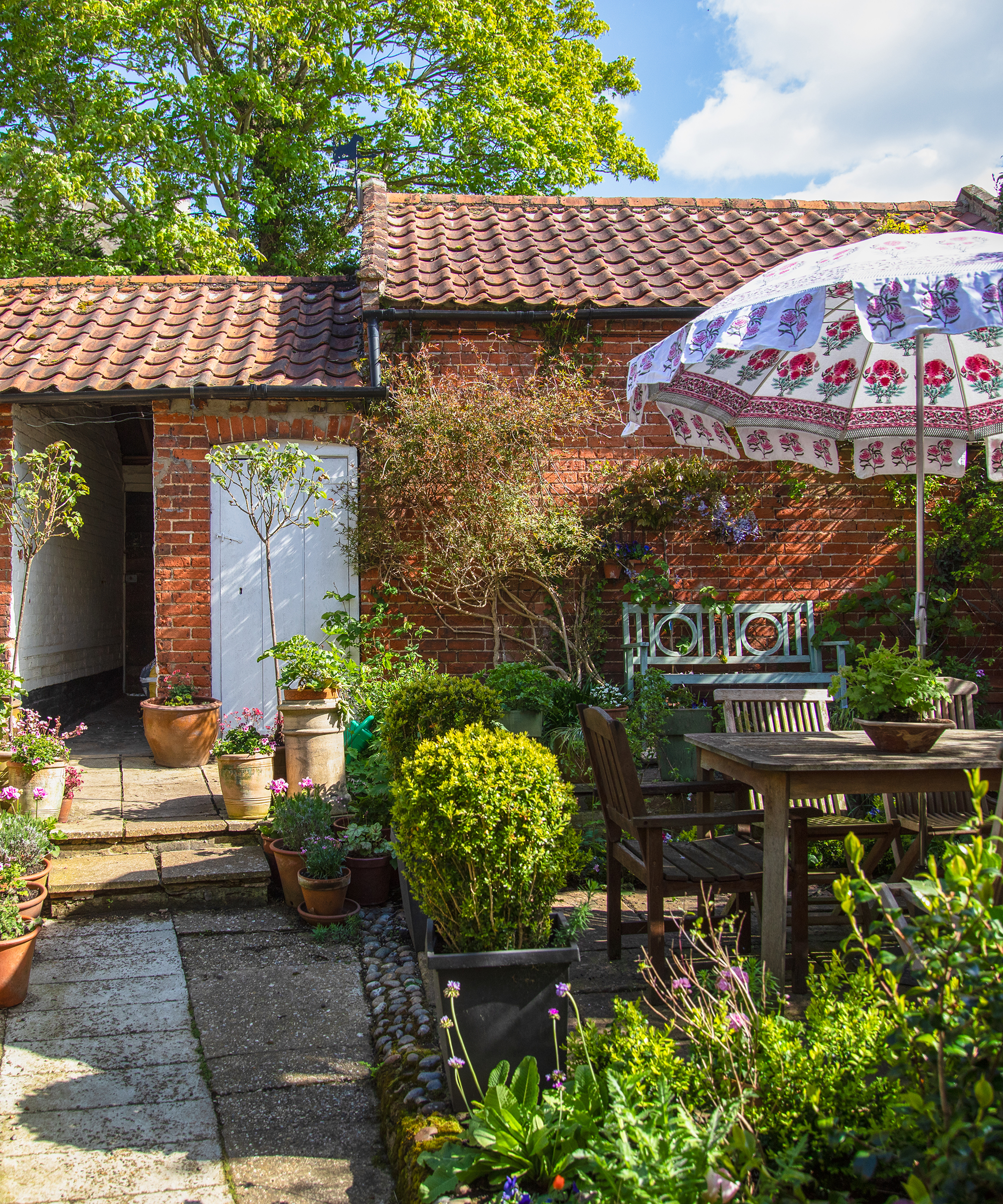 courtyard garden with old outbuildings and patterned parasol