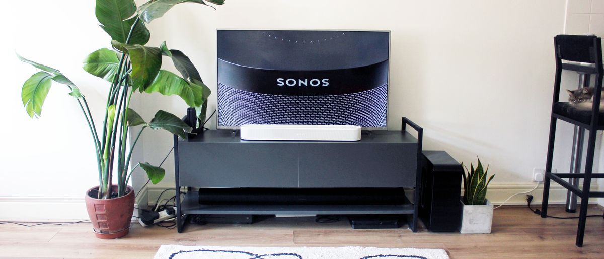 the sonos beam gen 2 soundbar in white pictured beneath a tv on a black cabinet