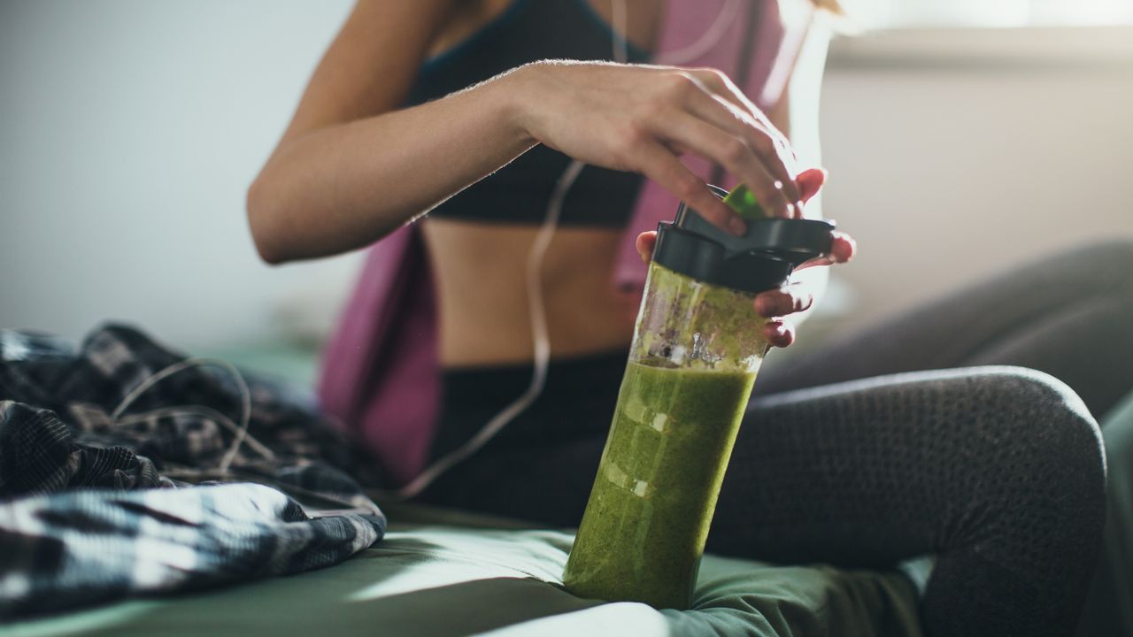 Woman in gym kit with green smoothie, work out on an empty stomach