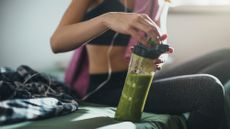 Woman in gym kit with green smoothie, work out on an empty stomach