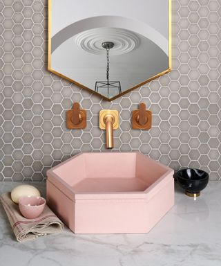 Wash station in small bathroom with pink sink and Ca Pietra sand mosaic tiles