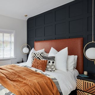 Bedroom with blue wall panelling and russet throw on the bed