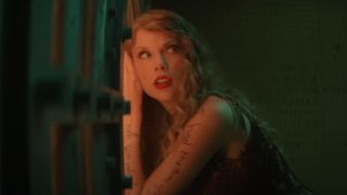 Taylor Swift, dressed as Speak Now, leaning against a vault trying to hear out of it.