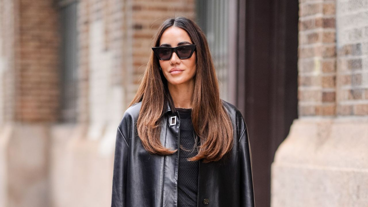 best hair conditioners - Tamara Kalinic wears sunglasses, a long black leather jacket , a black t-shirt, blue flared denim jeans pants, a black leather bag - getty images 2018040848