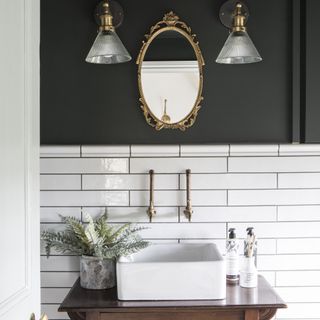 bathroom with white metro tiles and black walls with gold wall lights