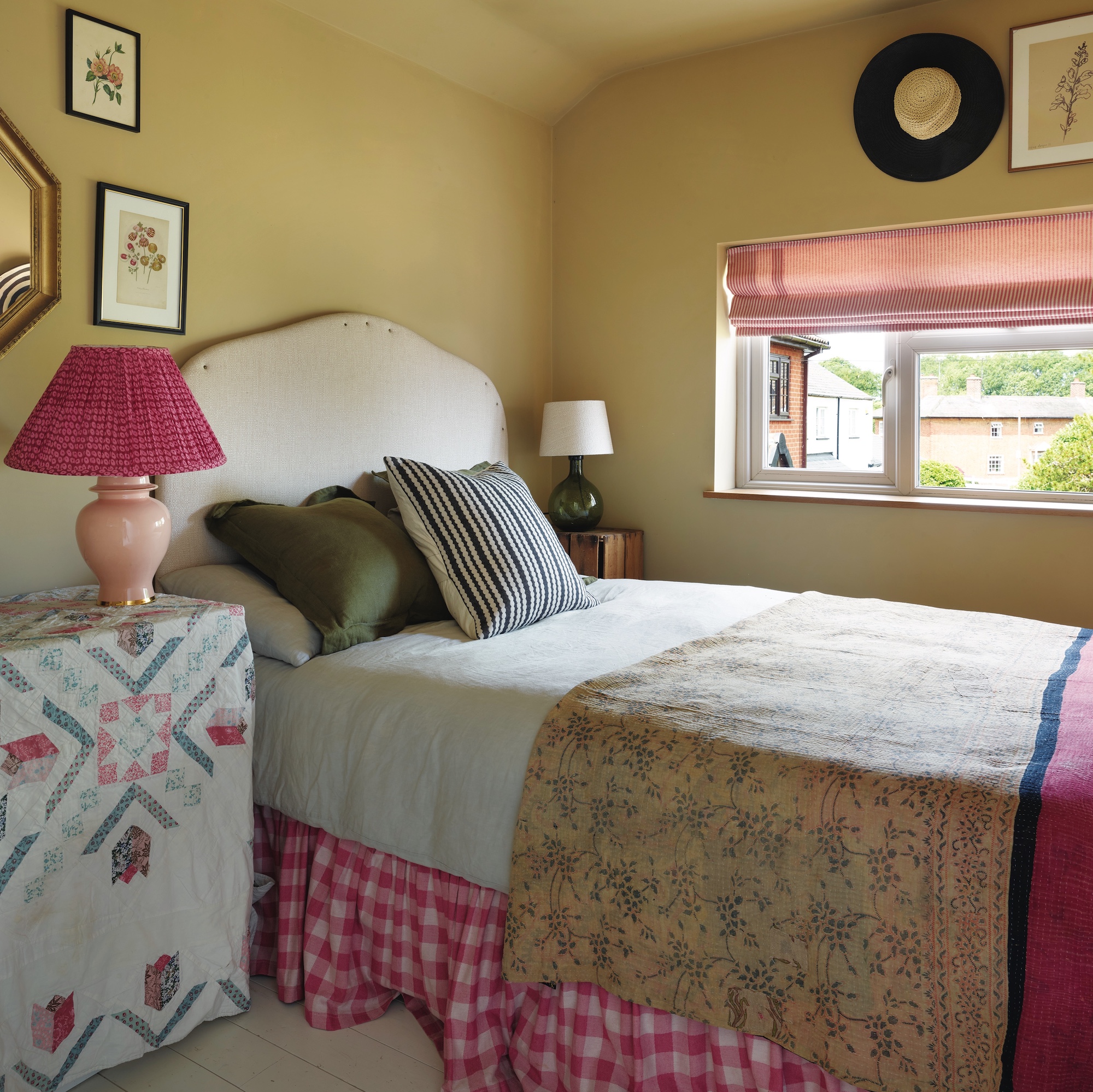 bedroom with pale yellow walls, bed with cream headboard and pink covers