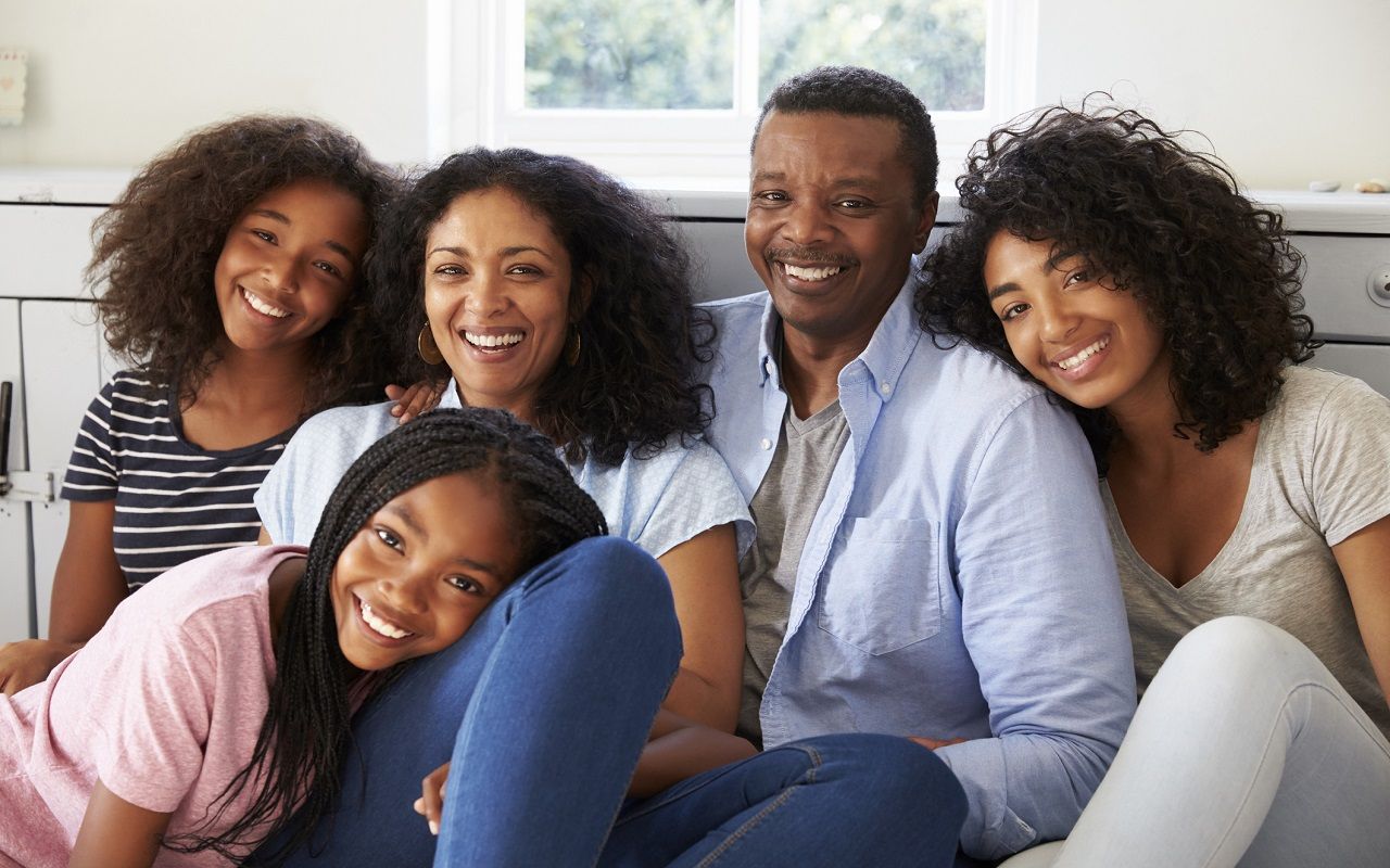 Portrait Of Smiling Family Relaxing On Seat At Home